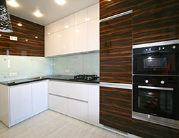 Кухня со встроенной бытовой техникой (посудомойка и холодильник скрыты фасадами). Однотонный кухонный фартук (окрашенное стекло).