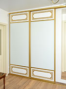 Шкаф-купе: фрезерованные вставки из МДФ и белый матовый лакобель. Патина золото.