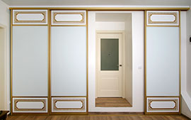 Шкаф-купе: фрезерованные вставки из МДФ и белый матовый лакобель. Патина золото.